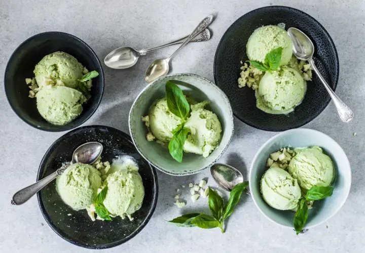 Coppette di gelato al basilico, guarnite con foglioline fresche e pezzetti croccanti. Un gusto inaspettato e rinfrescante.