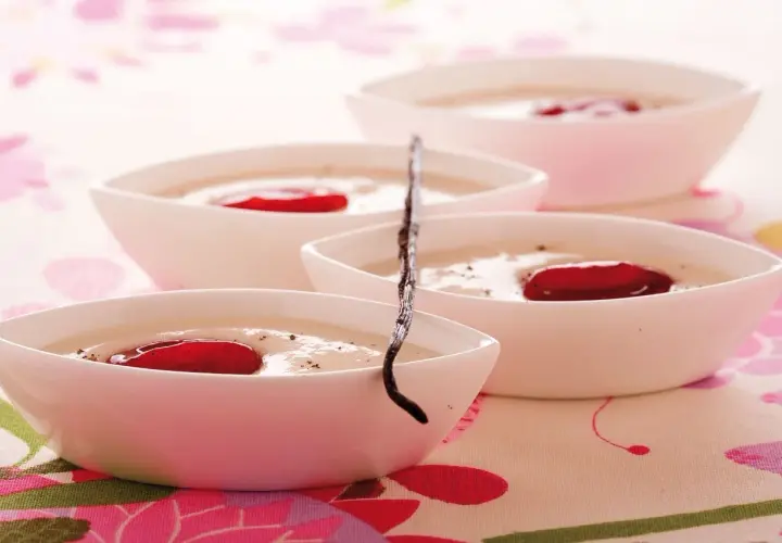 Deliziosa crema di riso in ciotoline bianche, guarnita con bacche rosse e un baccello di vaniglia.