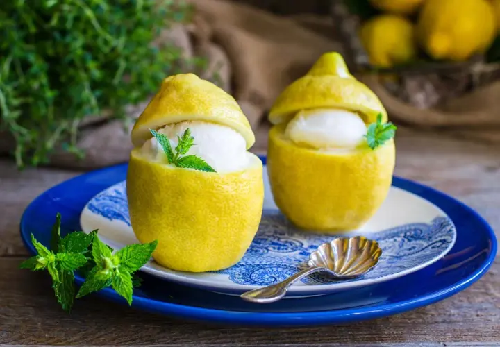 Due deliziosi gelati al limone serviti in limoni svuotati, guarniti con menta fresca. Un dessert rinfrescante e veloce.