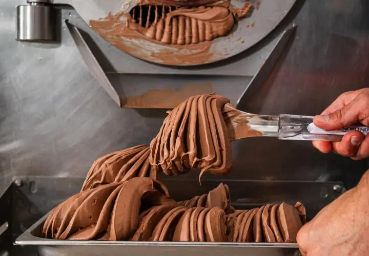 Gelato al cioccolato cremoso viene prelevato da una macchina, con destrosio additivo per la consistenza perfetta.