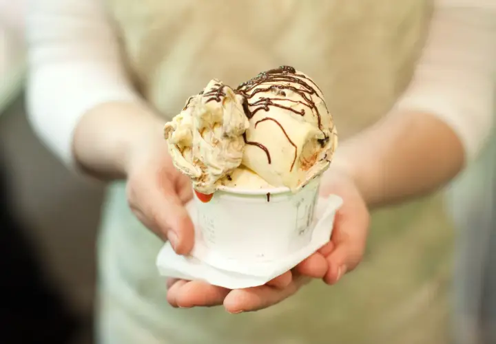 Un cono di gelato artigianale, con variegature e scaglie di cioccolato, pronto per essere gustato, un assaggio della storia del gelato.