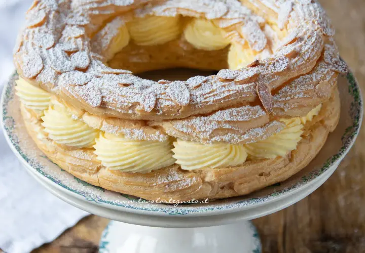 Un delizioso Paris Brest, un anello di pasta choux ripieno di crema pasticcera e guarnito con mandorle e zucchero a velo.