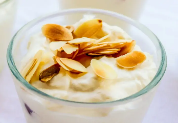 Deliziosa granita di mandorle in un bicchiere, guarnita con mandorle tostate a lamelle.