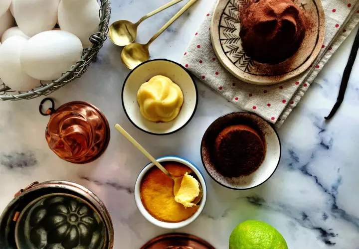 Un delizioso budino fatto in casa, pronto per essere gustato. Uova fresche, stampi in rame e una spolverata di cacao completano la scena.