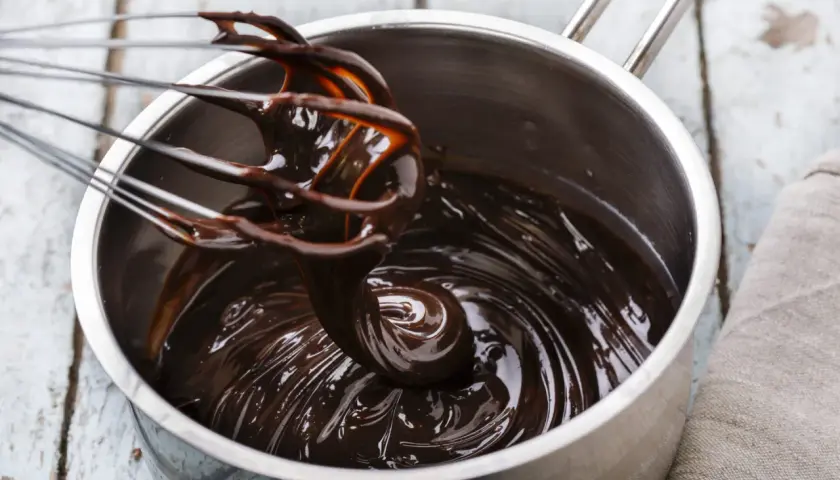 Cioccolato fuso lucido e cremoso in una pentola, pronto per essere usato. Scopri come mantenere liquido il cioccolato sciolto per dolci perfetti.