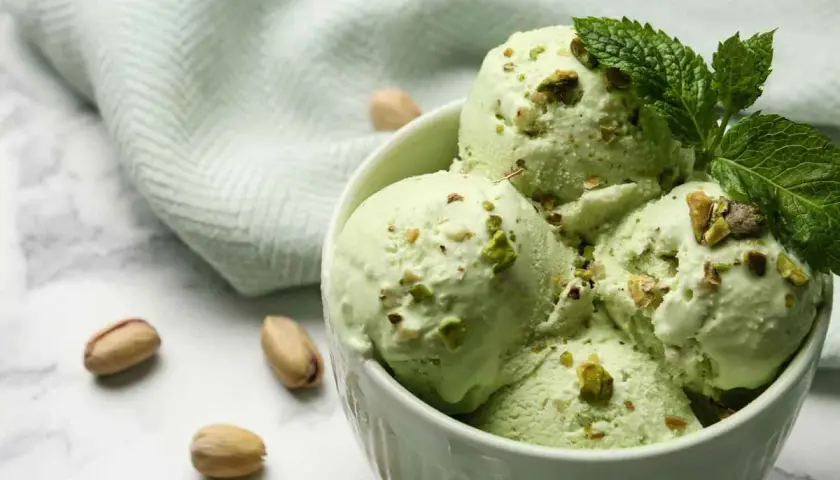 Coppa di gelato al pistacchio fatto in casa da Benedetta, guarnita con pistacchi tritati e foglioline di menta.