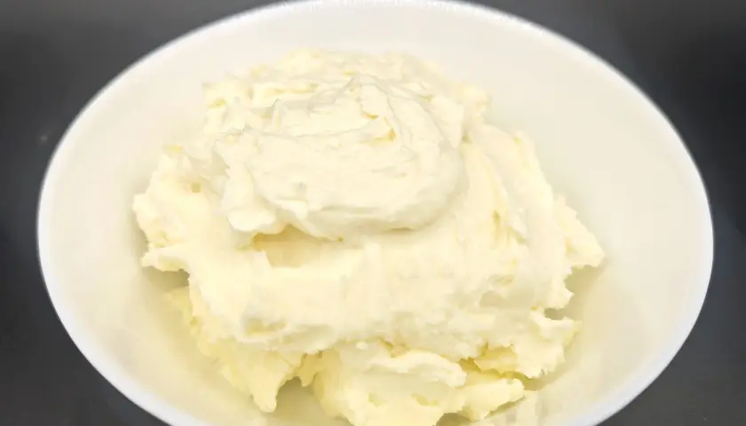 Un cremoso mascarpone fatto in casa con latte, servito in una ciotola bianca. La sua consistenza morbida e invitante promette delizie culinarie.