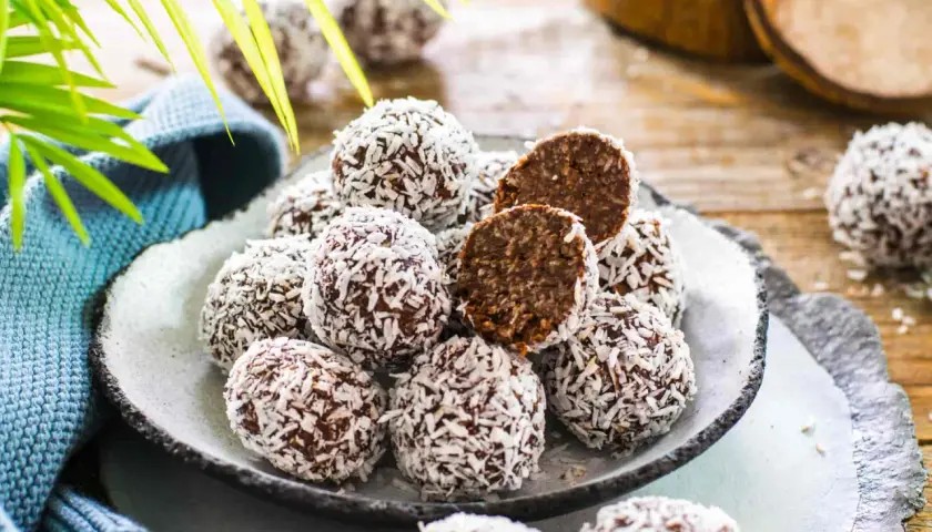 Un piatto pieno di golose palline di cocco, alcune intere, altre tagliate a metà per mostrare il ripieno scuro e invitante.