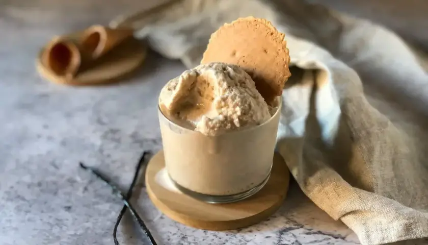 Delizioso gelato con panna vegetale, guarnito con un biscotto croccante e bacche di vaniglia.