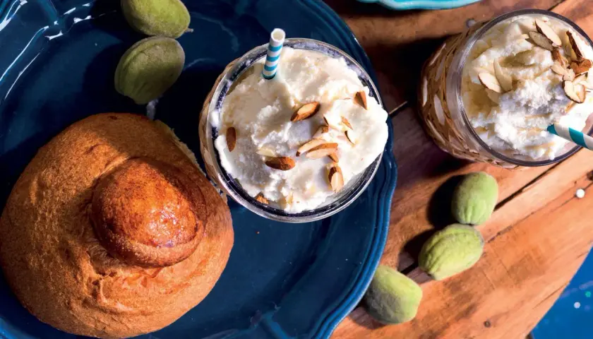 Deliziosa granita di mandorle con latte di mandorla, guarnita con mandorle a lamelle, accompagnata da un pane dolce e mandorle verdi.