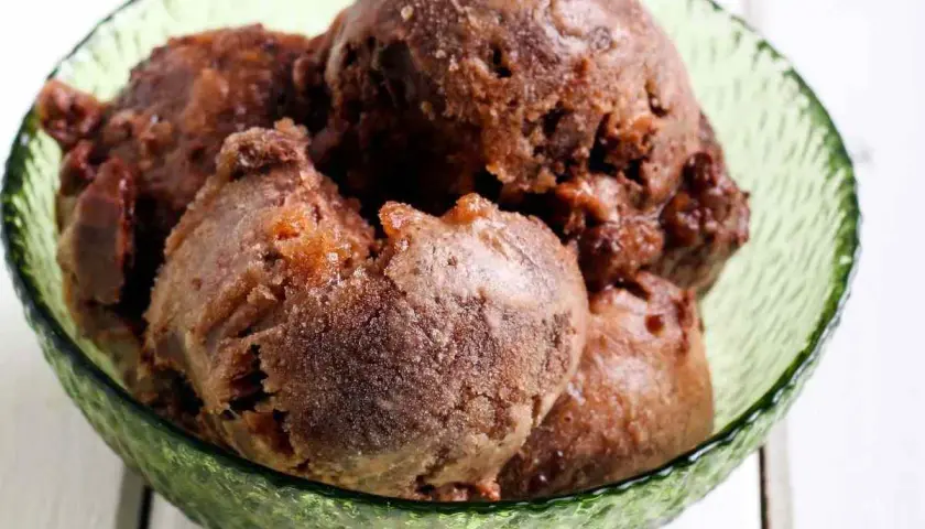 Coppa di sorbetto al cioccolato, con palline scure e invitanti, servite in una ciotola verde smeraldo.