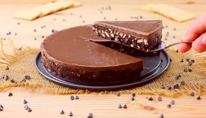 Una fetta di torta fredda con biscotti e cioccolato viene sollevata da una tortiera.