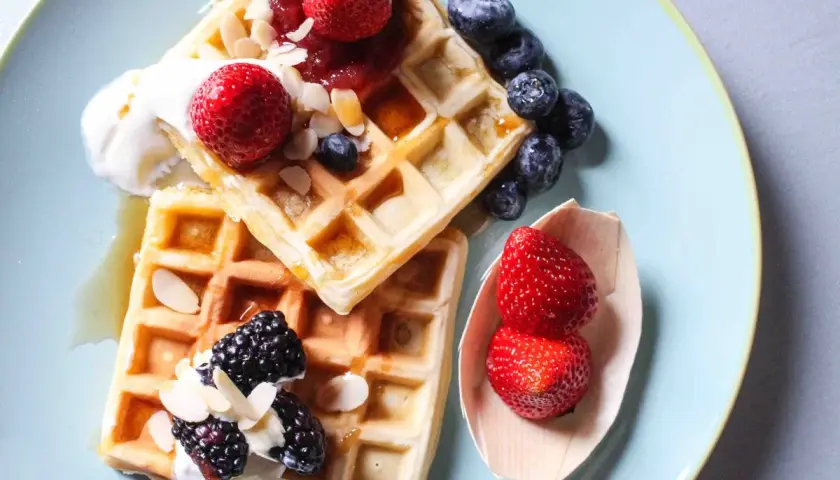 Waffle ricetta originale belga con fragole, mirtilli, more, panna e mandorle.