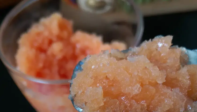 Granita all'arancia fatto in casa da Benedetta, fresca e dissetante, servita in un bicchiere e su un cucchiaio.