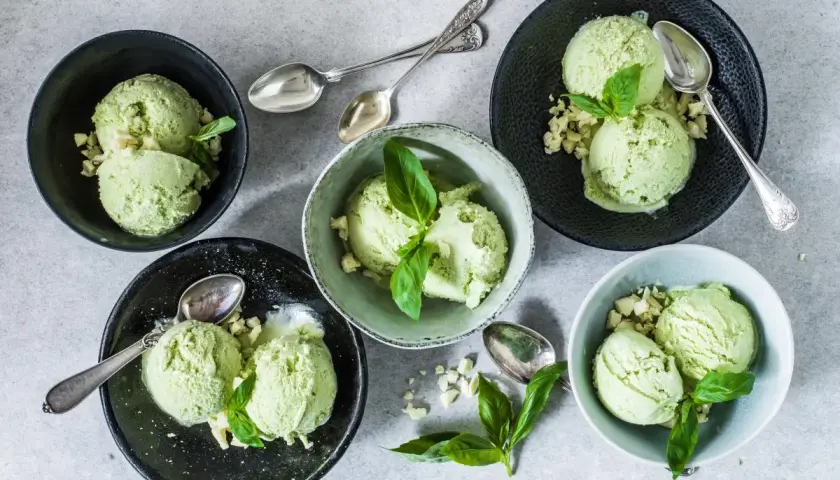 Coppette di gelato al basilico, guarnite con foglioline fresche e pezzetti croccanti. Un gusto inaspettato e rinfrescante.