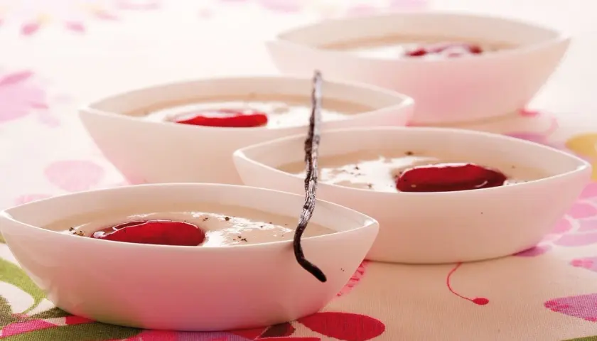 Deliziosa crema di riso in ciotoline bianche, guarnita con bacche rosse e un baccello di vaniglia.