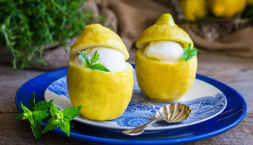 Due deliziosi gelati al limone serviti in limoni svuotati, guarniti con menta fresca. Un dessert rinfrescante e veloce.