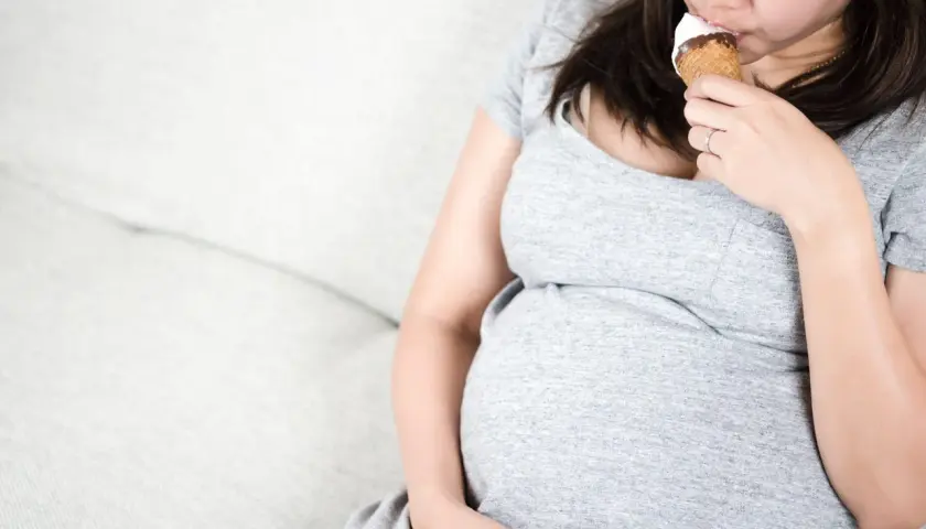 Donna incinta si gode un cono gelato, pensando a quali gusti scegliere.