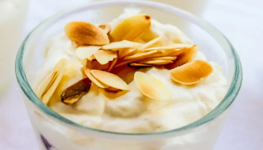 Deliziosa granita di mandorle in un bicchiere, guarnita con mandorle tostate a lamelle.