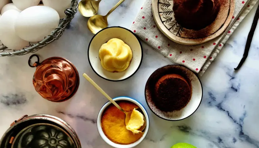 Un delizioso budino fatto in casa, pronto per essere gustato. Uova fresche, stampi in rame e una spolverata di cacao completano la scena.