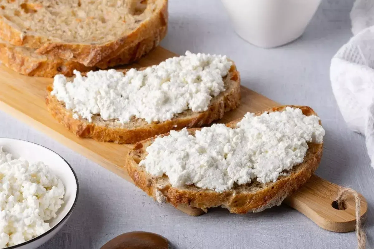 Fette di pane rustico con abbondante ricotta fresca, pronte per gustose ricette con ricotta.