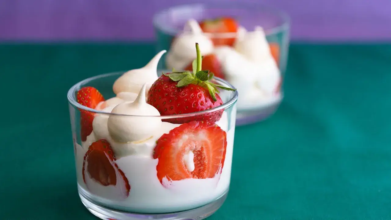 Coppette di fragole e gelato alla panna, guarnite con meringhe.