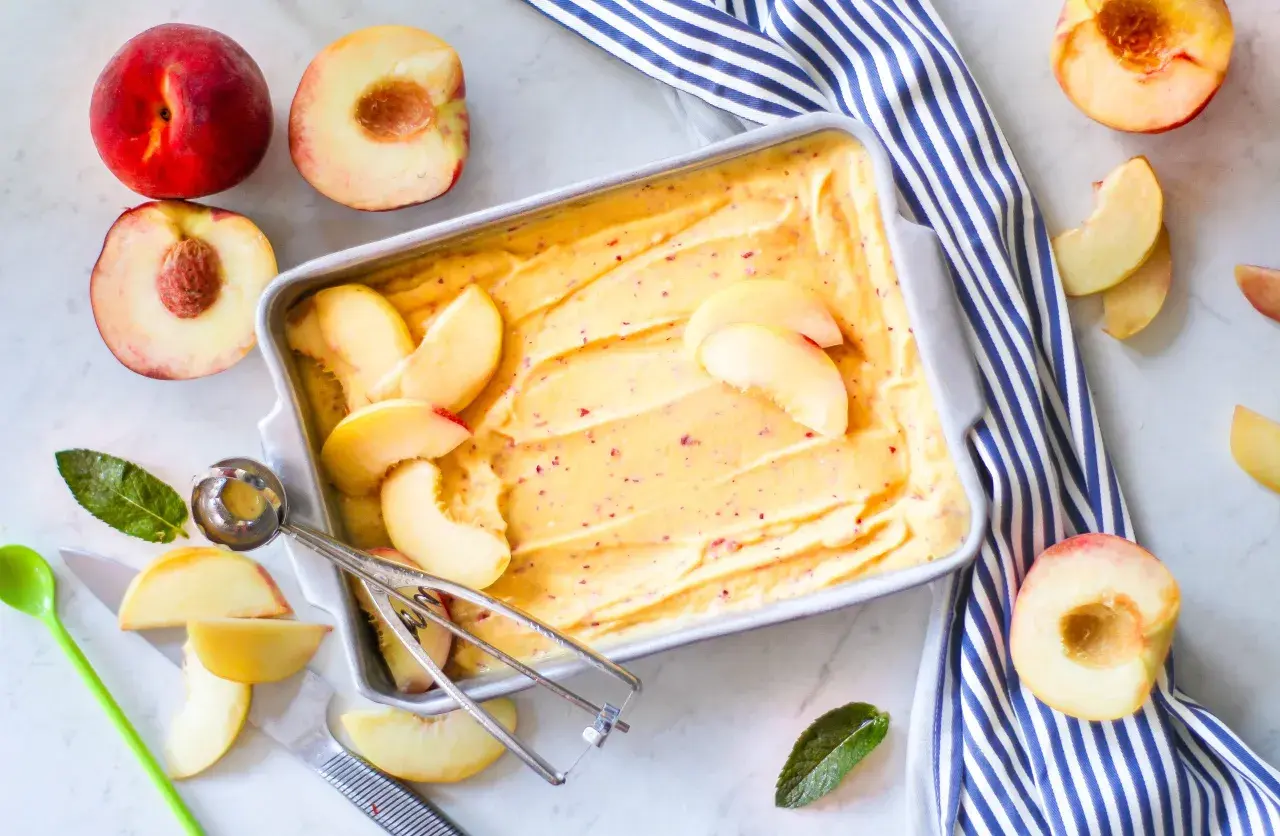 Sorbetto alla pesca fatto in casa, con pesche fresche e un cucchiaio per servirlo. Un dolce estivo rinfrescante.