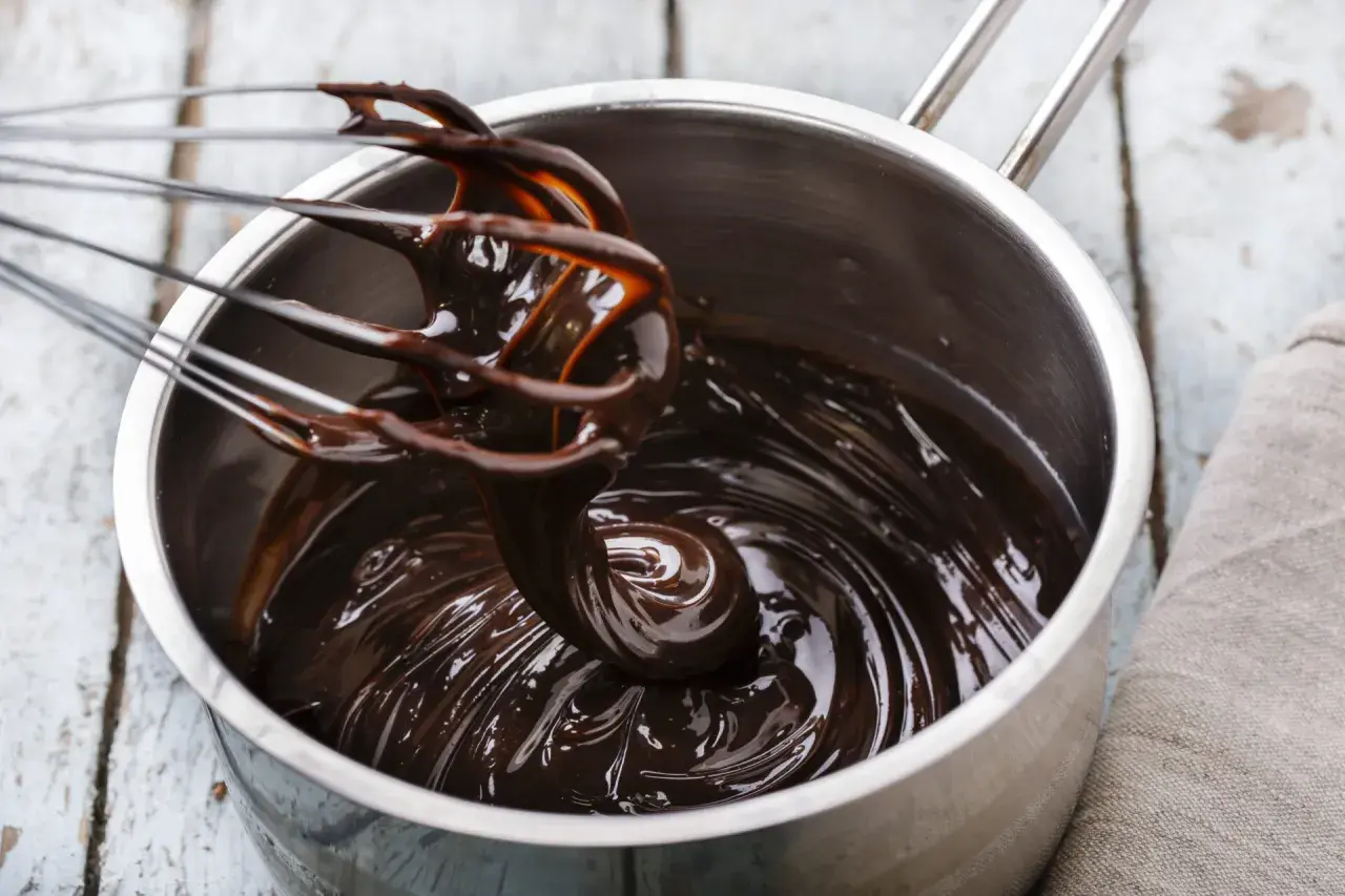 Cioccolato fuso lucido e cremoso in una pentola, pronto per essere usato. Scopri come mantenere liquido il cioccolato sciolto per dolci perfetti.