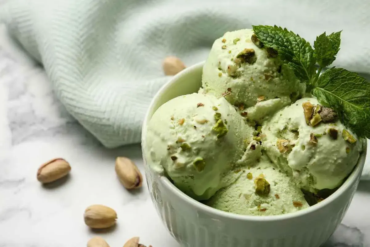 Coppa di gelato al pistacchio fatto in casa da Benedetta, guarnita con pistacchi tritati e foglioline di menta.