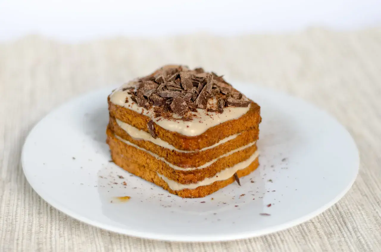 Una deliziosa torta tiramisù a più strati, ricoperta di crema e scaglie di cioccolato fondente.