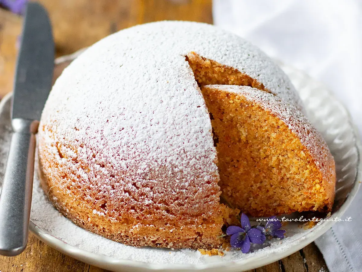 Torta Camilla ricetta originale: soffice torta cosparsa di zucchero a velo, con una fetta tagliata che rivela l'interno dorato e profumato.