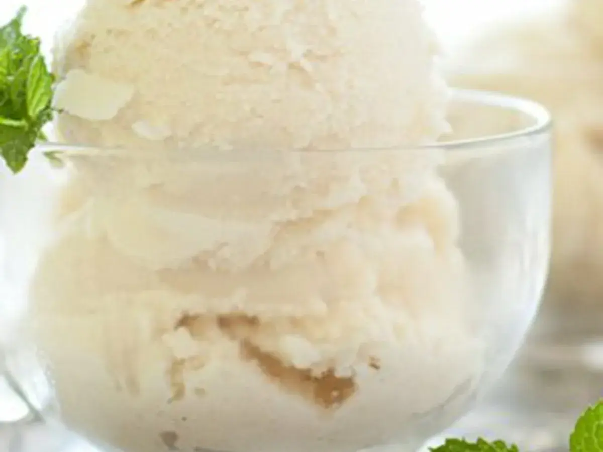 Coppa di gelato alla vaniglia, preparato con panna scremata, guarnita con foglioline di menta fresca.