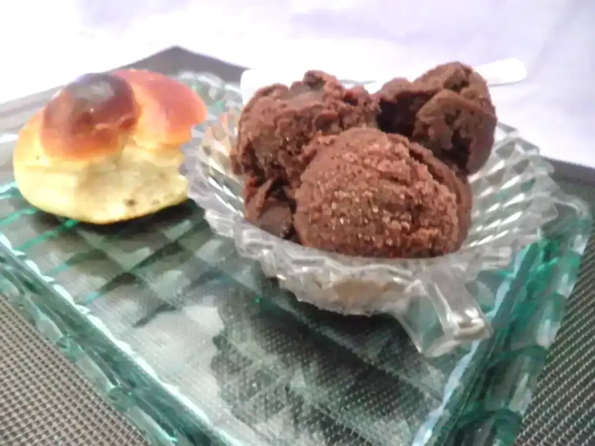 Un dolce pane intrecciato accanto a una coppa di granita cioccolato, serviti su un piatto di vetro.