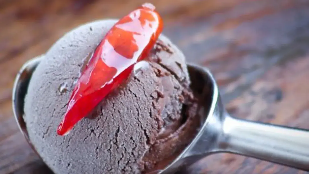 Un cucchiaio di gelato al cioccolato con una decorazione di peperoncino rosso lucido. Un'esplosione di dolcezza e piccantezza.