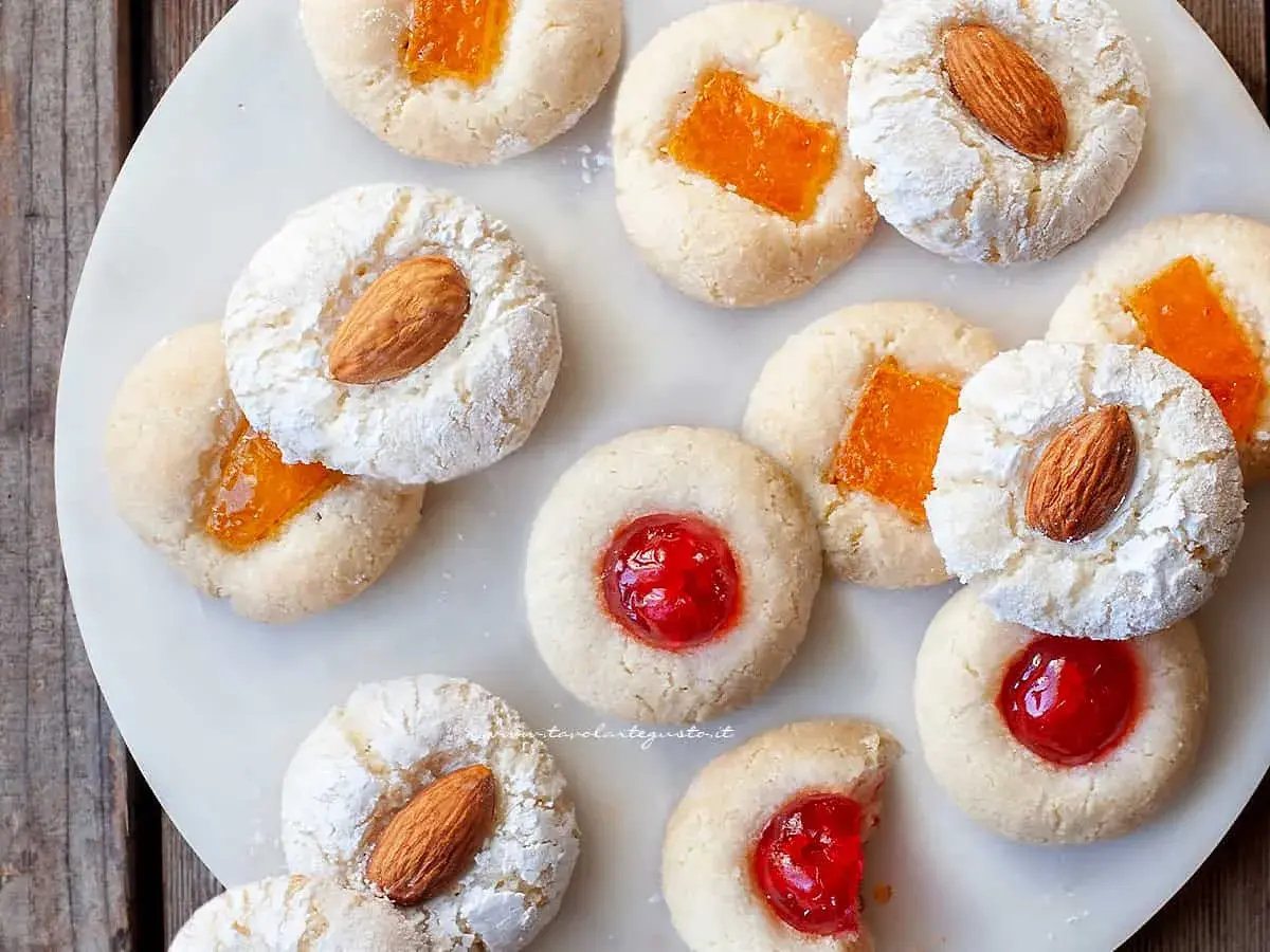 Biscotti con mandorle e marmellata, alcuni spolverati di zucchero a velo, ricordano un delizioso sorbetto alla mandorla.