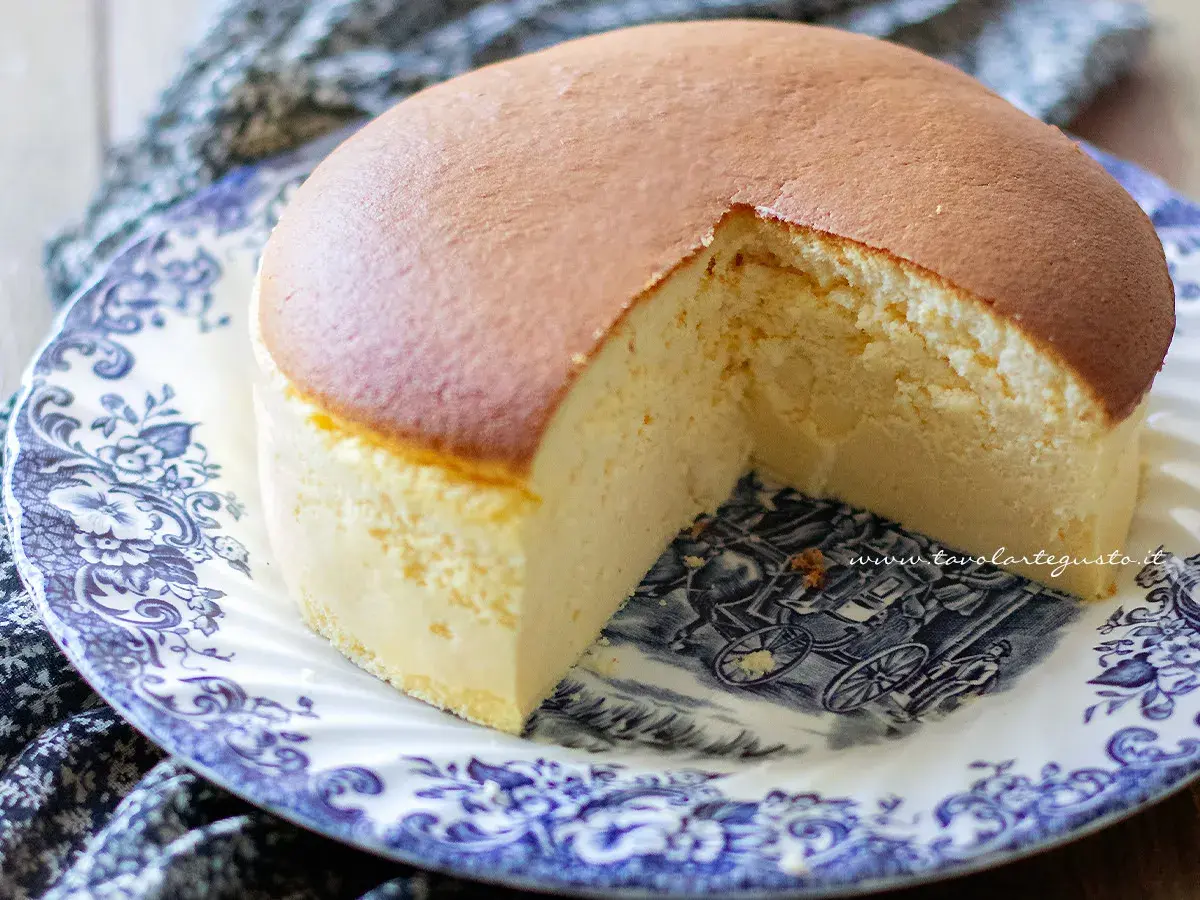 Una soffice torta giapponese, dorata in superficie e chiara all'interno, servita su un piatto decorato con un paesaggio in stile antico.