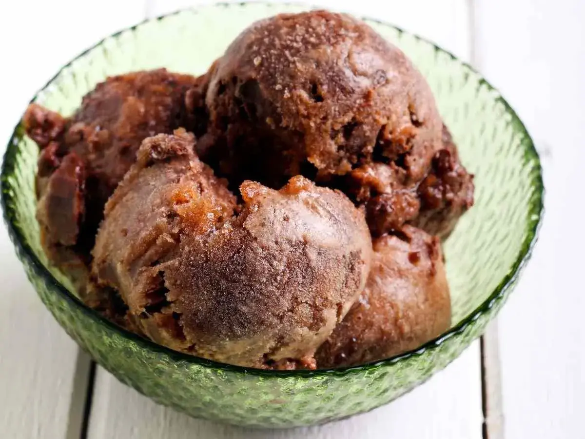Coppa di sorbetto al cioccolato, con palline scure e invitanti, servite in una ciotola verde smeraldo.