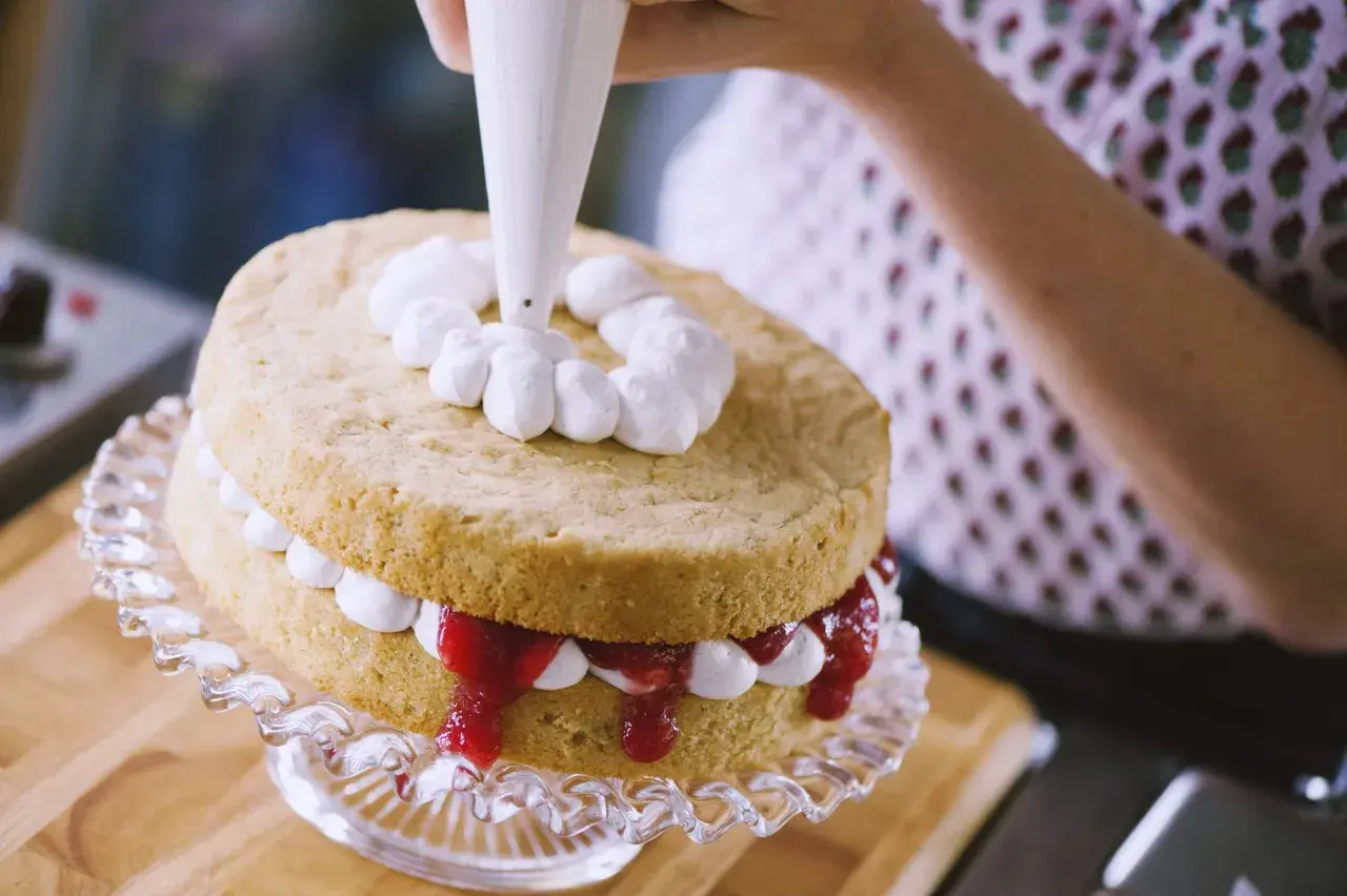 Decorazione di una torta con panna fresca montata. La differenza tra panna fresca e panna da cucina è evidente nella consistenza e nel risultato finale.