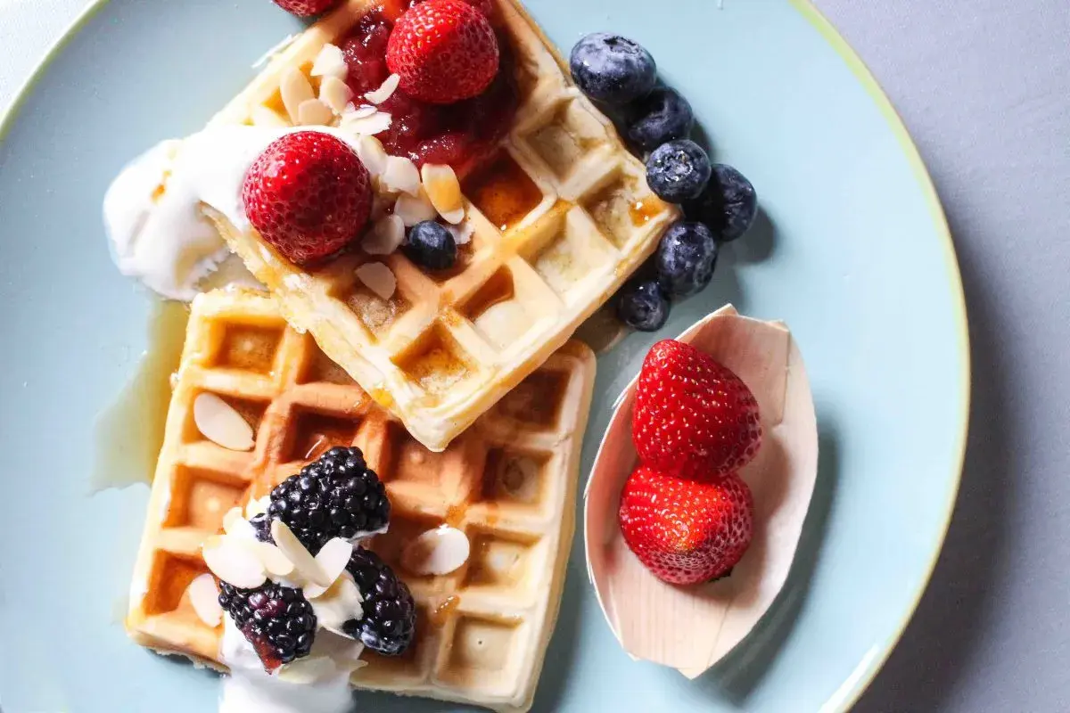 Waffle ricetta originale belga con fragole, mirtilli, more, panna e mandorle.