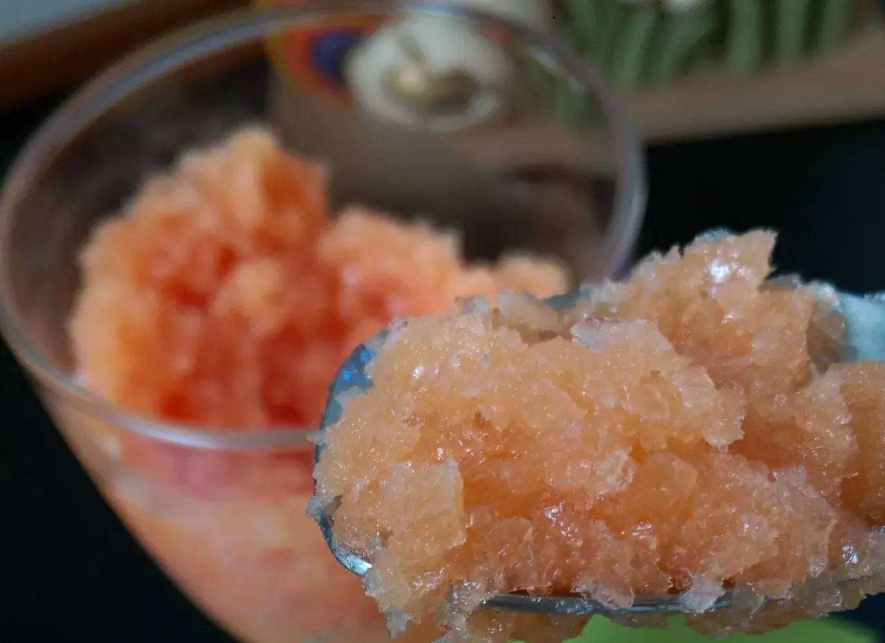 Granita all'arancia fatto in casa da Benedetta, fresca e dissetante, servita in un bicchiere e su un cucchiaio.