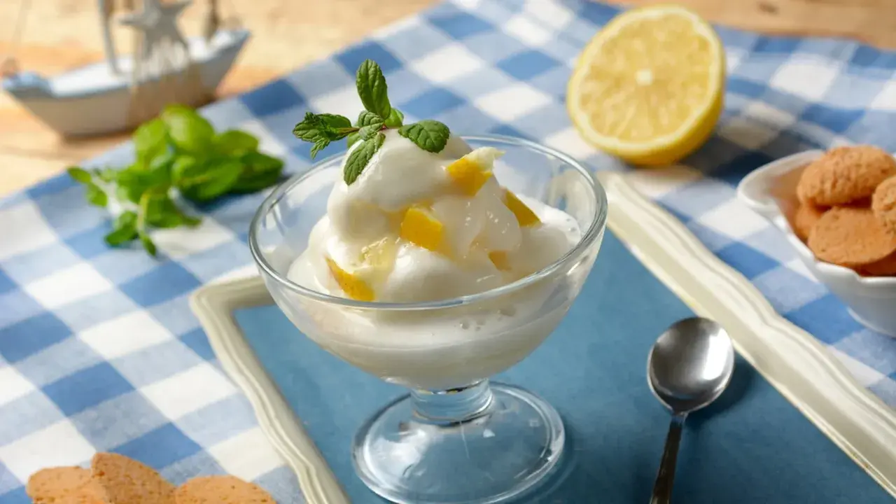 Sorbetto al limone, fresco e cremoso, preparato con la gelatiera, guarnito con menta e scorzette.