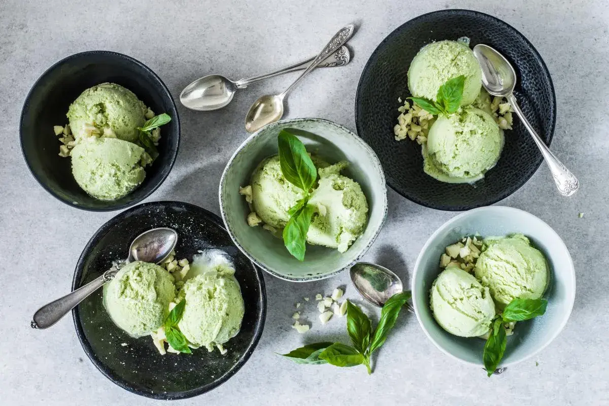 Coppette di gelato al basilico, guarnite con foglioline fresche e pezzetti croccanti. Un gusto inaspettato e rinfrescante.