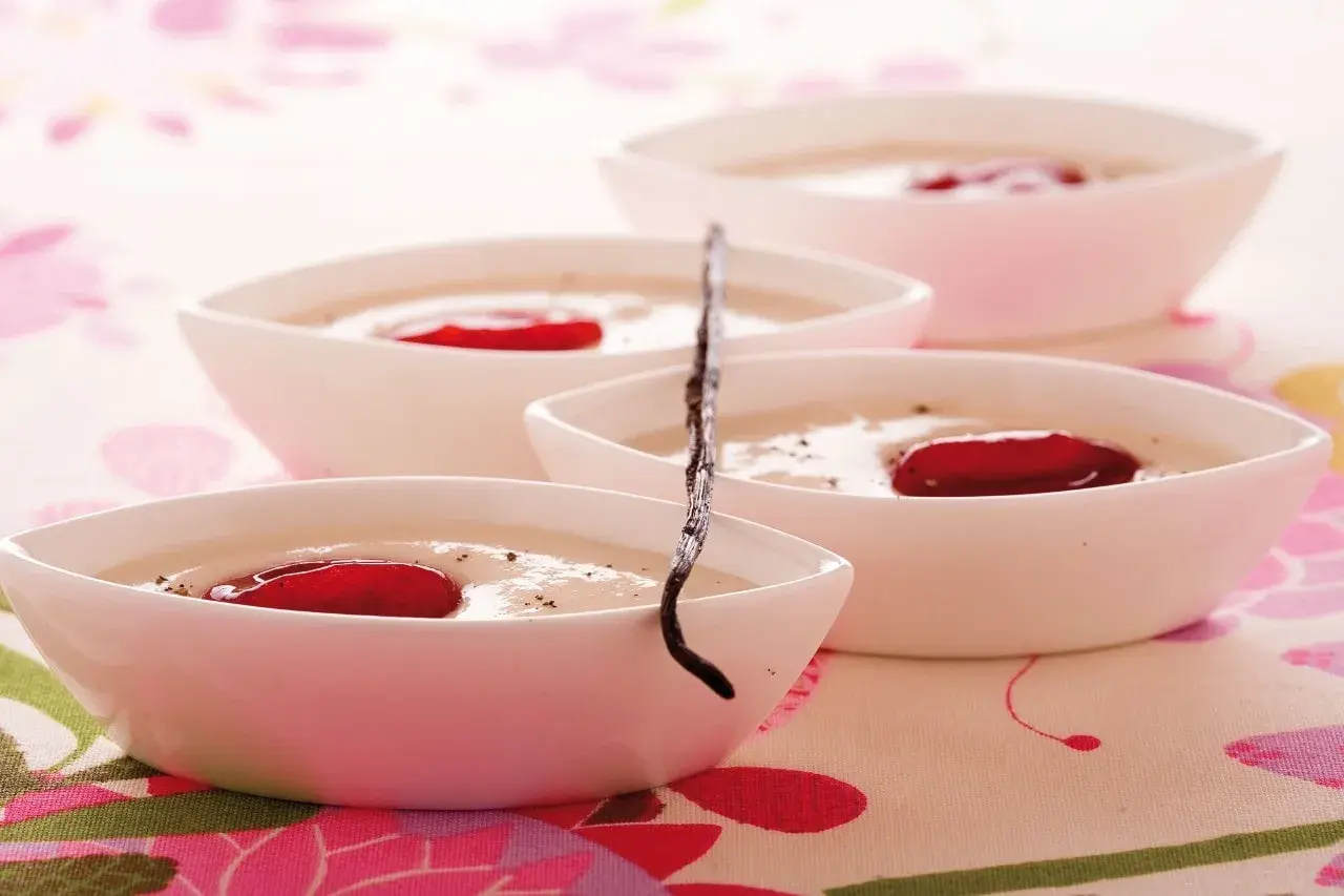 Deliziosa crema di riso in ciotoline bianche, guarnita con bacche rosse e un baccello di vaniglia.