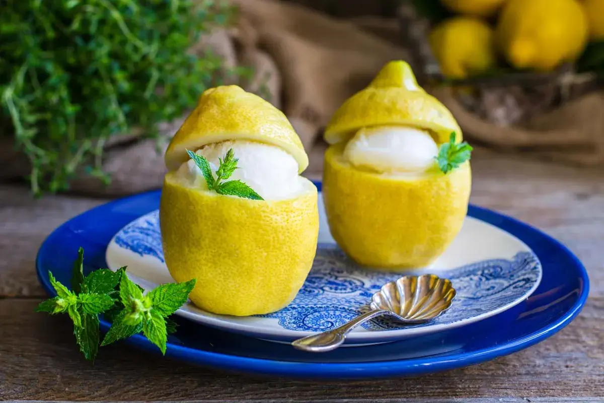 Due deliziosi gelati al limone serviti in limoni svuotati, guarniti con menta fresca. Un dessert rinfrescante e veloce.