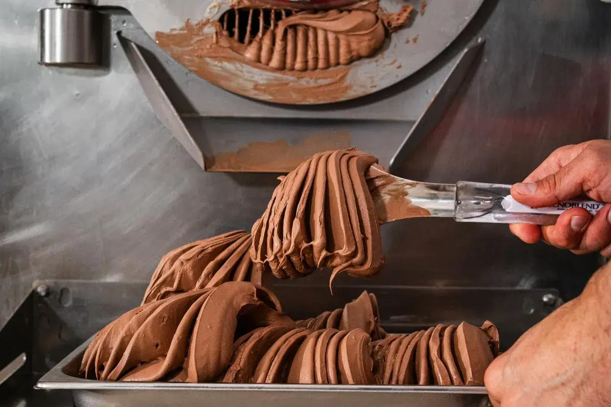 Gelato al cioccolato cremoso viene prelevato da una macchina, con destrosio additivo per la consistenza perfetta.