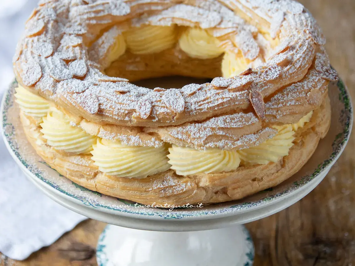 Un delizioso Paris Brest, un anello di pasta choux ripieno di crema pasticcera e guarnito con mandorle e zucchero a velo.