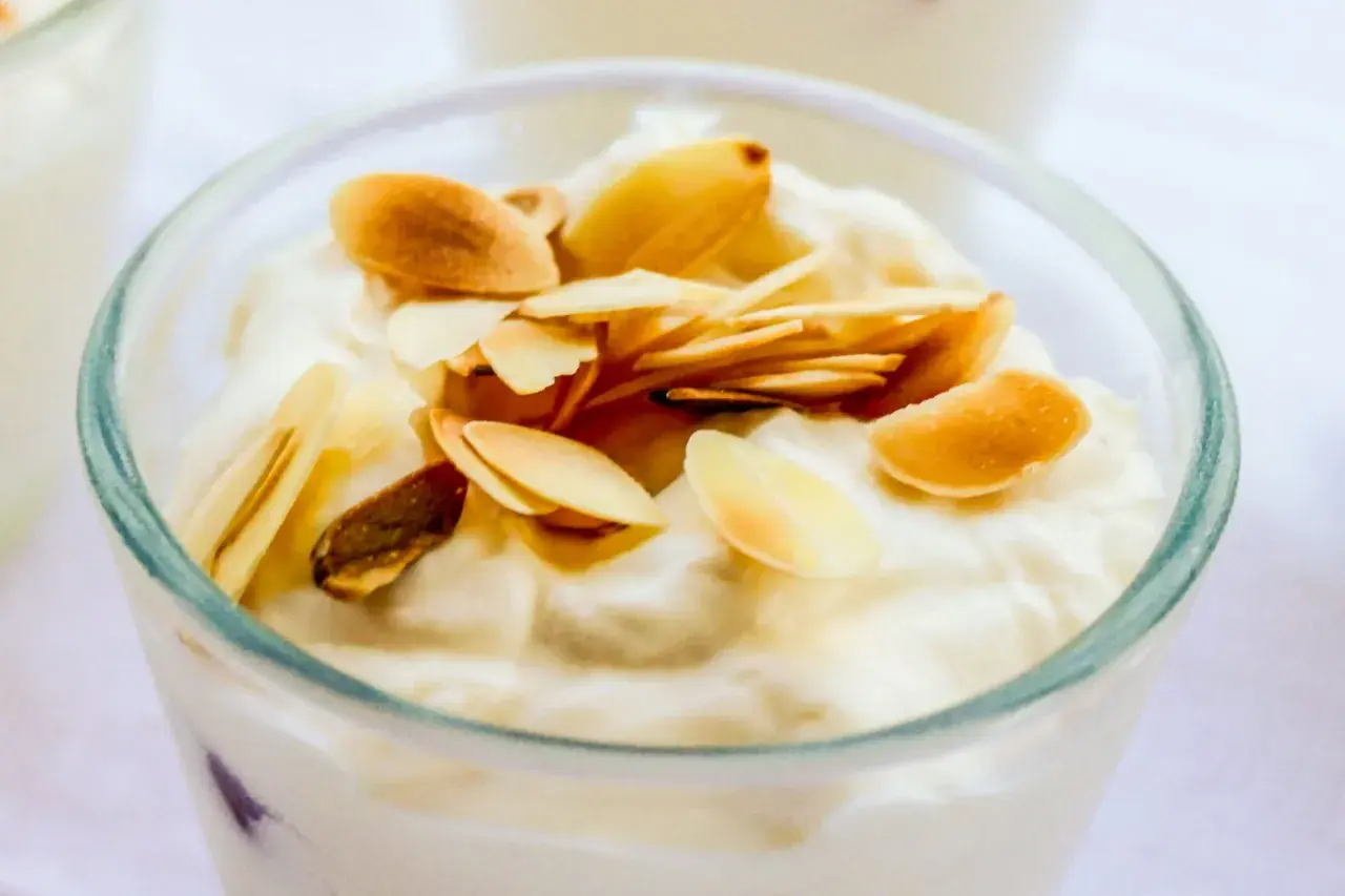 Deliziosa granita di mandorle in un bicchiere, guarnita con mandorle tostate a lamelle.