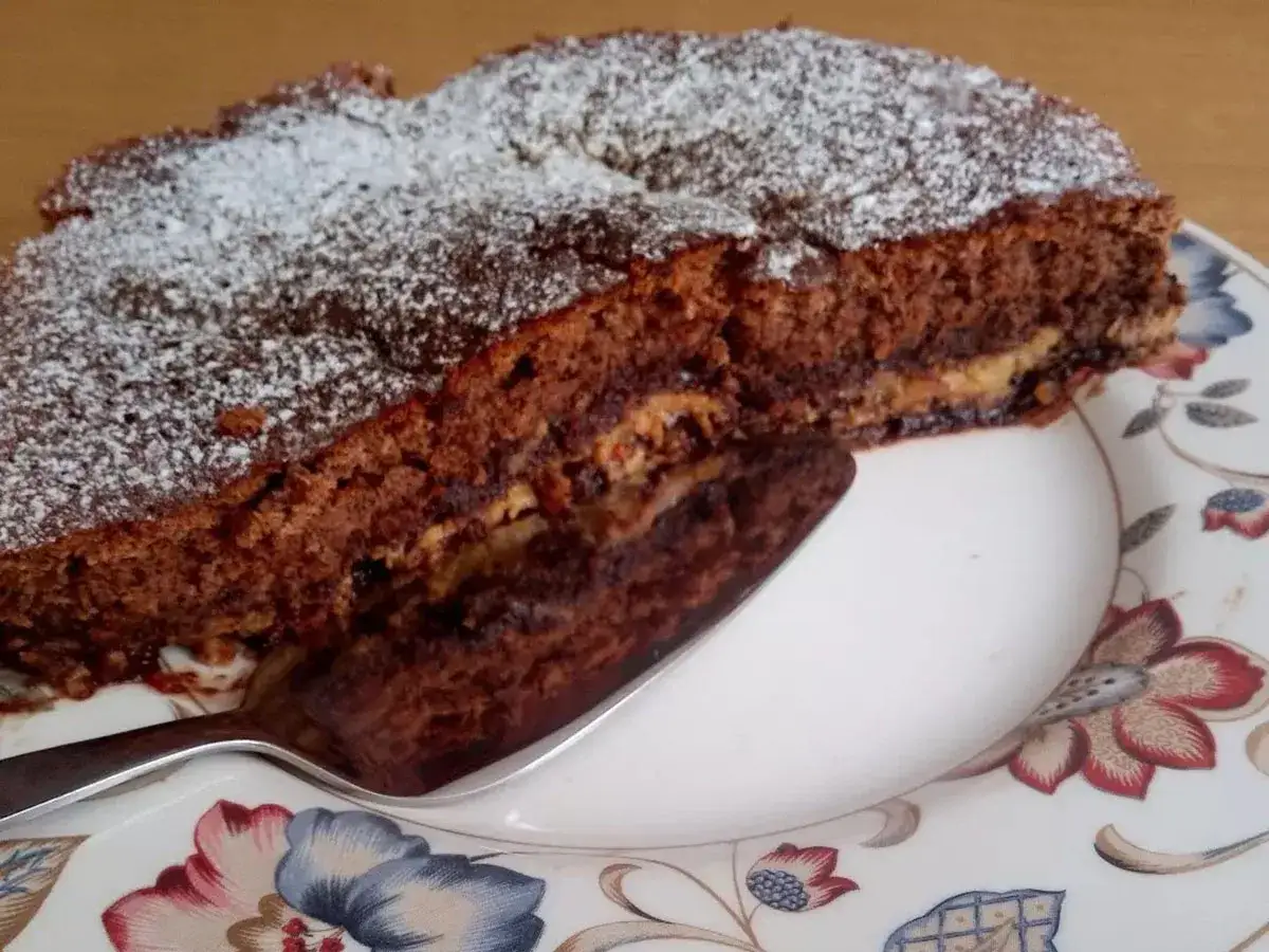 Una fetta di crescionda spoletina, dolce al cioccolato cosparso di zucchero a velo, su un piatto fiorito.