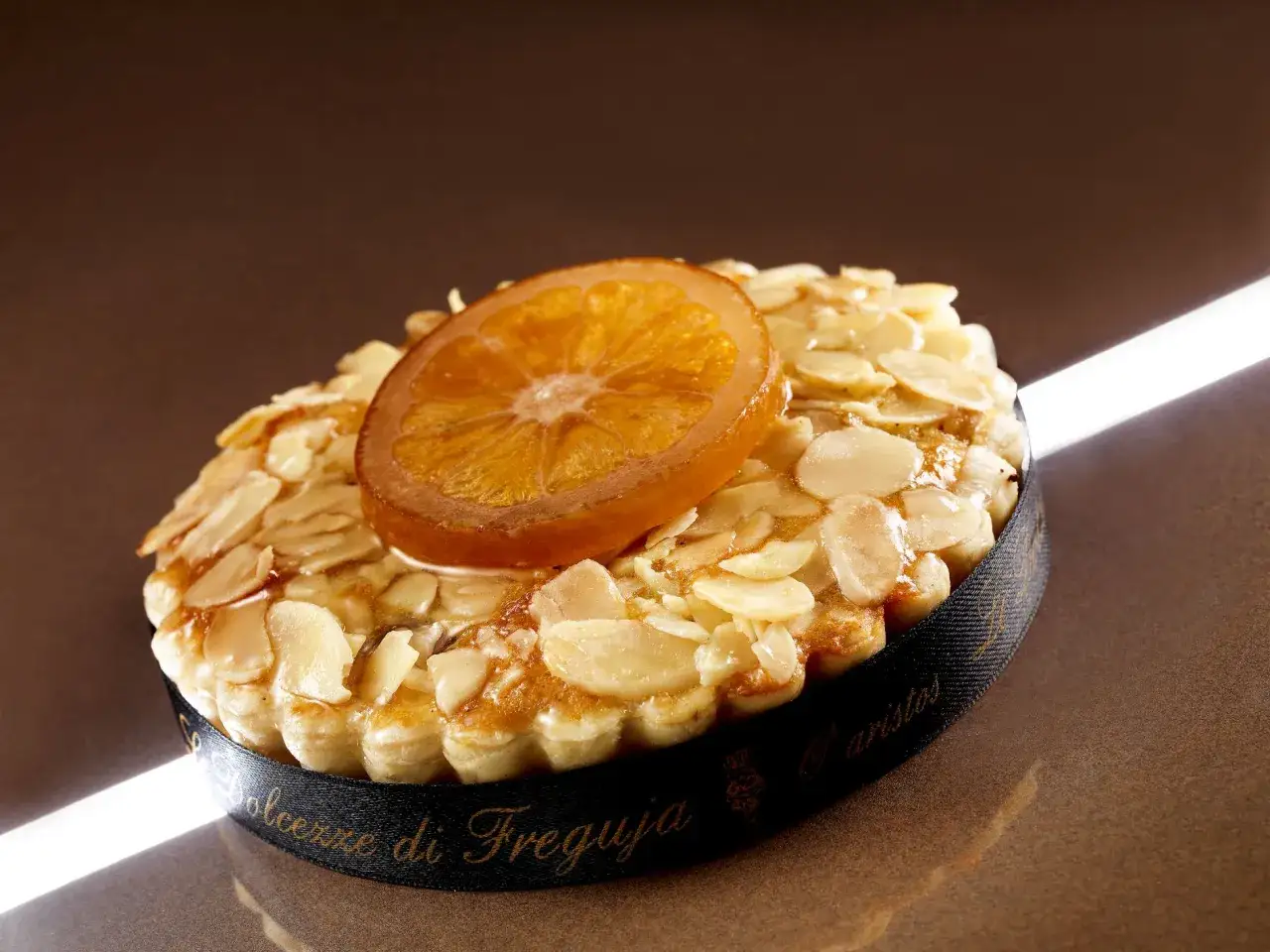 Delizioso dolce con mandorle a lamelle e una fetta d'arancia candita, che ricorda un sorbetto alla mandorla.