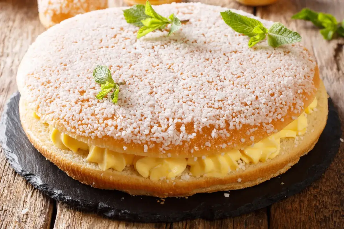 Una deliziosa polacca aversana, soffice e ripiena di crema gialla, decorata con zuccherini e foglioline di menta.